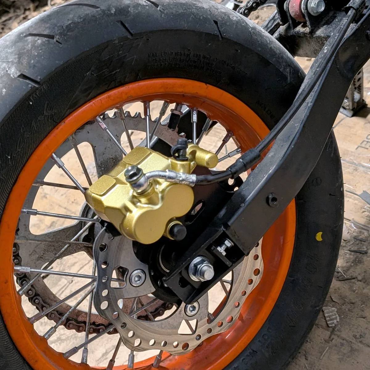A gold brake caliper on an orange rim, close up